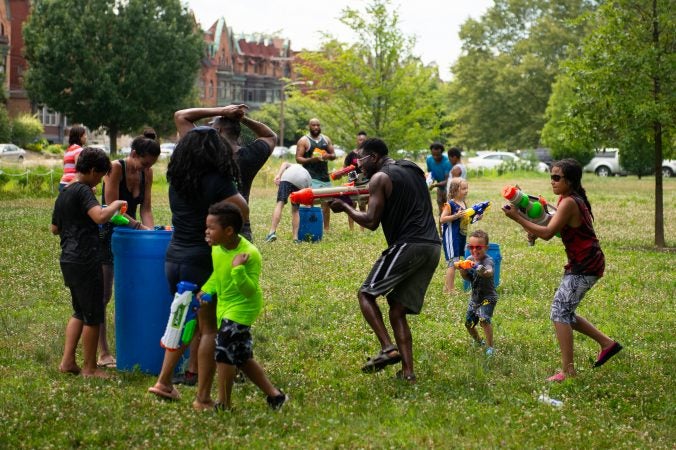 Gabriel Nyantakyi, center, sprays his water gun on unsuspecting participants in Water Fight Philly on Sunday, June 30, 2019. Nyantakyi organized the event, held in Fairmount Park, to encourage young people to put down their firearms and participate in safe, fun activities. (Kriston Jae Bethel for WHYY)