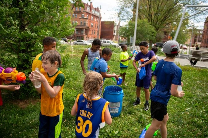 A group of children gather around a water refill station during the Water Fight Philly event on Sunday, June 30, 2019. (Kriston Jae Bethel for WHYY)