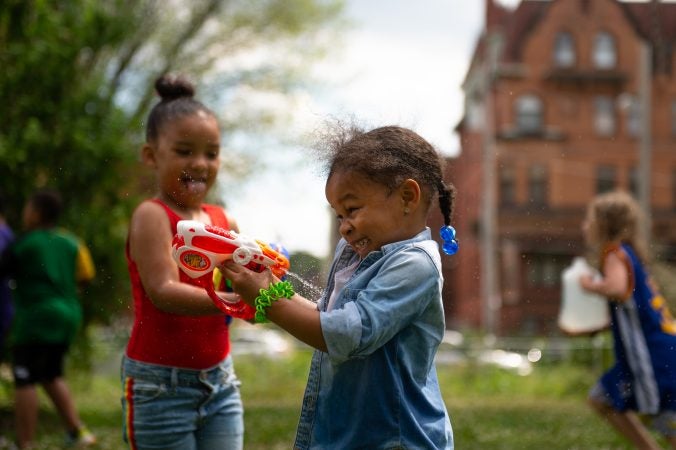 Morgan Johnson is sprayed by her cousin, Noor Slaughter, during the Water Fight Philly event on Sunday, June 30, 2019. (Kriston Jae Bethel for WHYY)