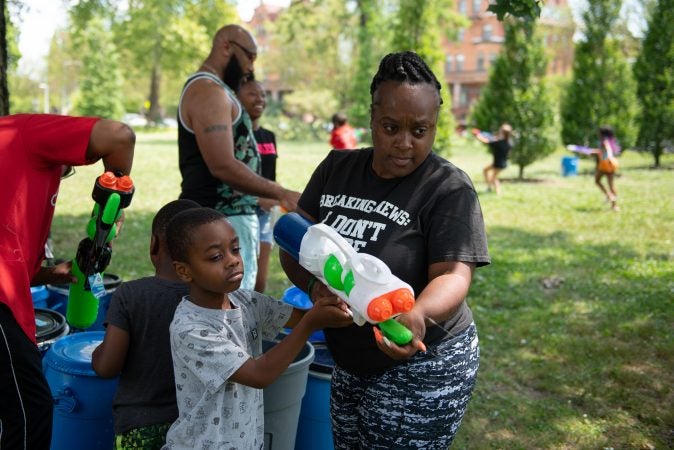 Cameron Anderson gets help from his mother, LaKesha, to fill up and test his water gun for Water Fight Philly on Sunday, June 30, 2019. (Kriston Jae Bethel for WHYY)