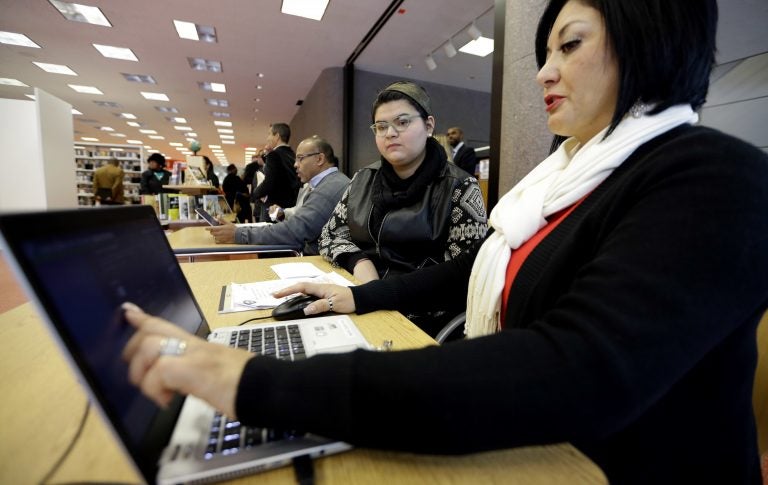 In this Friday, Nov. 14, 2014 file photo, Affordable Care Act health insurance marketplace navigator Leticia Chaw, right, helps gather information for Jennifer Sanchez to re-enroll in a health insurance plan in Houston. (David J. Phillip/AP Photo)