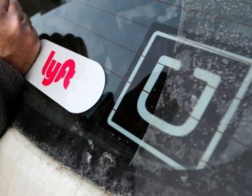 A Lyft logo is installed on a Lyft driver's car next to an Uber sticker
