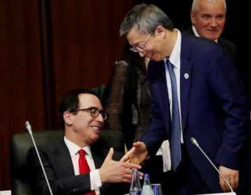 China's Central Bank Governor Yi Gang shakes hands with U.S. Treasury Secretary Steve Mnuchin, (left), during the G20 Finance Ministers and Central Bank Governors Meeting Saturday, June 8, 2019, In Fukuoka, Japan. (Kim Kyung-hoon/Pool Photo via AP)