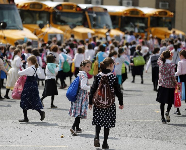 In this July 1, 2014 file photo, Orthodox Jewish girls walk to waiting buses after summer day camp in Kiryas Joel, N.Y. Kiryas Joel is a tightly packed Hasidic enclave surrounded by suburbia in the Hudson Valley. As a measles outbreak stretches toward summer camp season, New York counties with a concentration of Orthodox Jewish camps are requiring vaccinations for campers and staff. (Mike Groll/AP Photo)