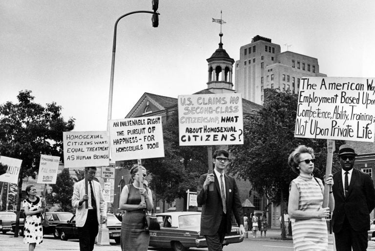 FILE - In this July 4, 1967 file photo Kay Tobin Lahusen, right, and other demonstrators carry signs calling for protection of homosexuals from discrimination as they march in a picket line in front of Independence Hall in Philadelphia. In 2019, same-sex marriage is the law of the land in the U.S. and at least 25 other countries. LGBT Americans serve as governors, big-city mayors and members of Congress, and one _ Pete Buttigieg _ is waging a spirited campaign for president. (AP Photo/John F. Urwiller)