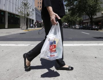 A woman walks with a plastic bag