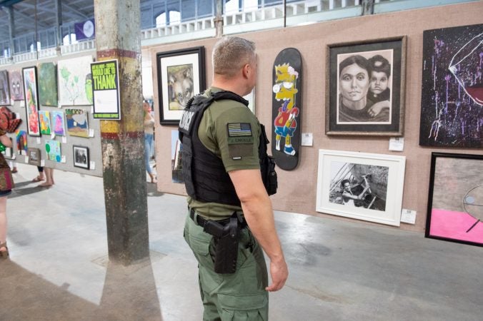 A member of the police force overseeing the event inspects a skateboard which featured a painted Bart Simpson on it. (Jonathan Wilson for WHYY)