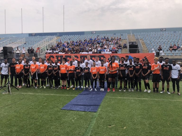 Members of the Philadelphia Union stand behind members of the new Chester High School soccer team that will start playing this fall. The major league soccer team announced Wednesday that they will support a high school soccer program for the Chester-Upland School District in Delaware County. (P. Kenneth Burns/WHYY)