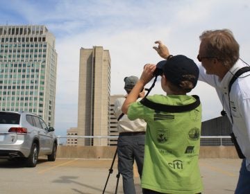 Bill Stewart of the Delaware Ornithological Society shows a young bird watcher where to see a falcon roosting on top of a building in downtown Wilmington. (Mark Eichmann/WHYY)