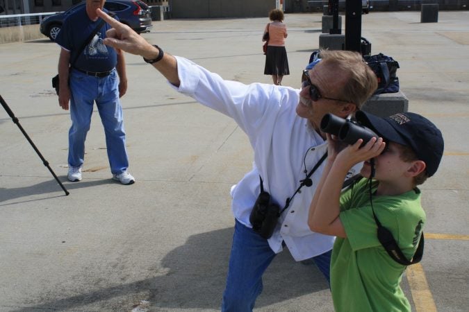 Bill Stewart of the Delaware Ornithological Society shows a young bird watcher where to see a falcon roosting on top of a building in downtown Wilmington. (Mark Eichmann/WHYY)