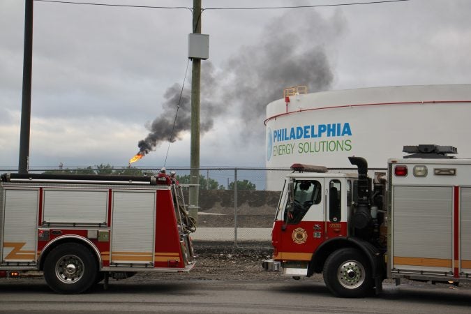 At the scene from a fire staging area under the Platt Bridge, a flare can be seen burned off fuel   (Emma Lee/WHYY)