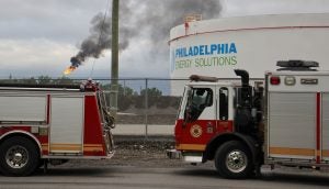 At the scene from a fire staging area under the Platt Bridge, a flare can be seen burned off fuel   (Emma Lee/WHYY)