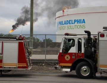 At the scene from a fire staging area under the Platt Bridge, a flare can be seen burned off fuel   (Emma Lee/WHYY)