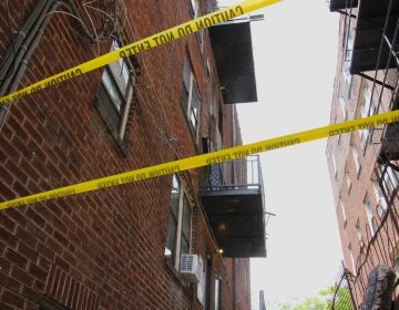 Caution tape surrounds an area at a building where a third-floor balcony collapsed, critically injuring two men. (Emma Lee/WHYY)