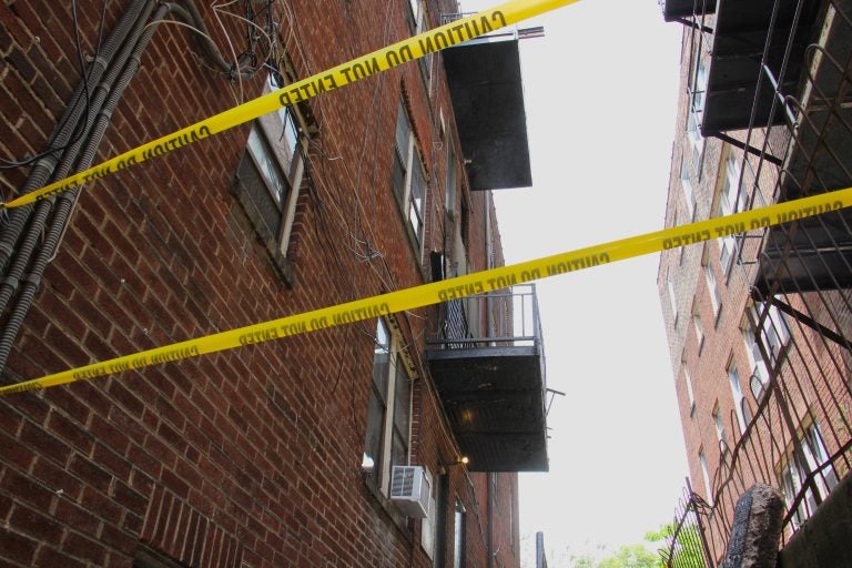 Caution tape surrounds an area at a building where a third-floor balcony collapsed, critically injuring two men. (Emma Lee/WHYY)