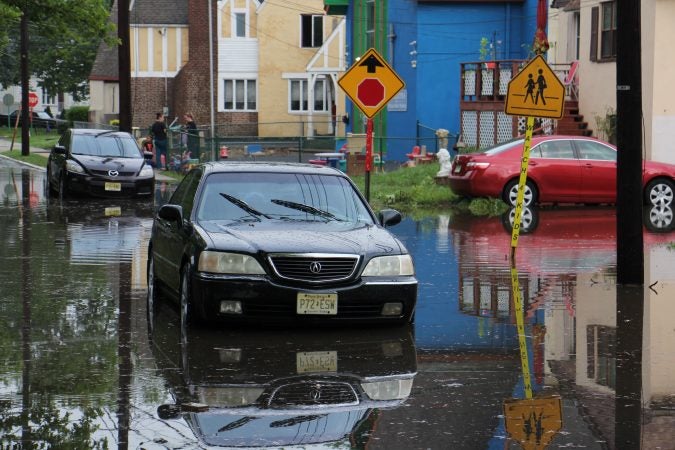 A car sits abandoned on a flooded Duncan Avenue in Westville, New Jersey. (Emma Lee/WHYY )