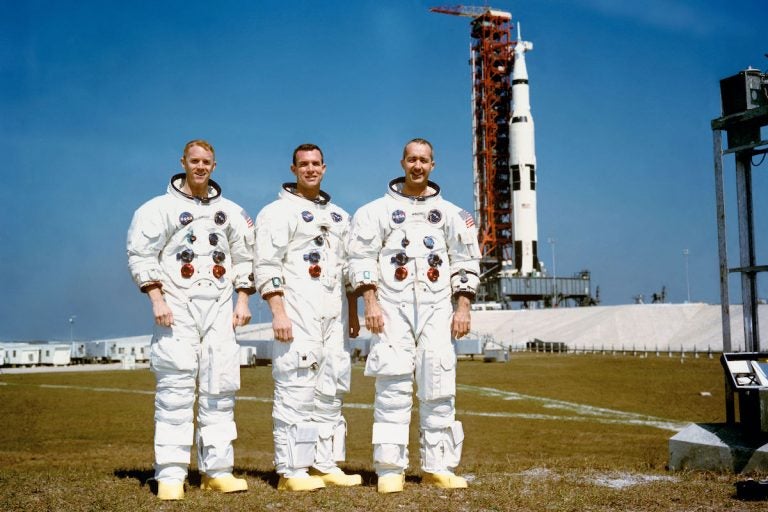 These three astronauts are the prime crew of the Apollo 9 Earth-orbital space mission. Left to right, are Russell L. Schweickart, lunar module pilot; David R. Scott, command module pilot; and James A. McDivitt, commander. In the right background is the Apollo 9 space vehicle on Pad A, Launch Complex 39, Kennedy Space Center (KSC). They are pausing momentarily during training for their scheduled 10-day mission. (NASA)