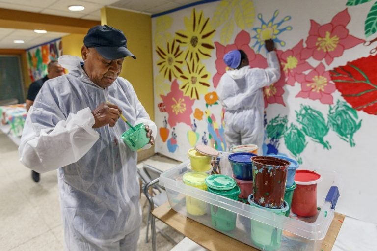 Tyrone Webb stirs green paint in a small room in Suburban Station. He's painting as part of the Same Day Work program. (Michael Bryant/Philadelphia Inquirer)