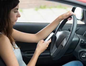 Side View Of Young Woman Using Mobile Phone While Driving Car