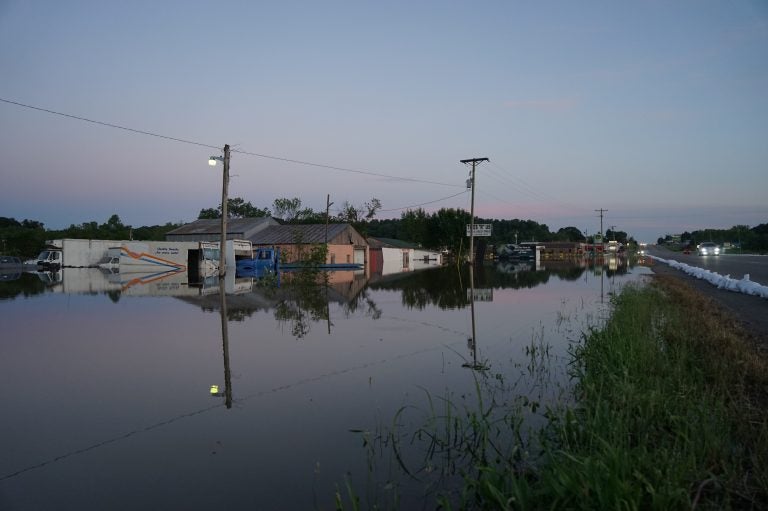 Floodwaters from the Arkansas River line either side of a road in Russellville, Arkansas, engulfing businesses and vehicles. (Nathan Rott/NPR)