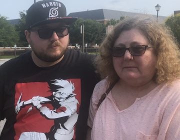 Christi Dewar, a survivor of the Virginia Beach mass shooting, stands with her son, Charles Dewar III, next to the office complex where a gunman killed 12 and injured several others on Friday. (Bobby Allyn/NPR)