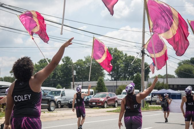Flag twirlers from the Fusion Marching Band perform for the thousands of people lining the two-mile parade route of the Marple Newtown Fourth of July parade. (Emily Cohen for WHYY)