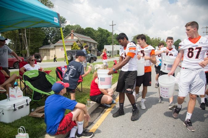 Members of the Marple Newtown High School football team walk along the parade route collecting donations to help support the annual Fourth of July parade. (Emily Cohen for WHYY)