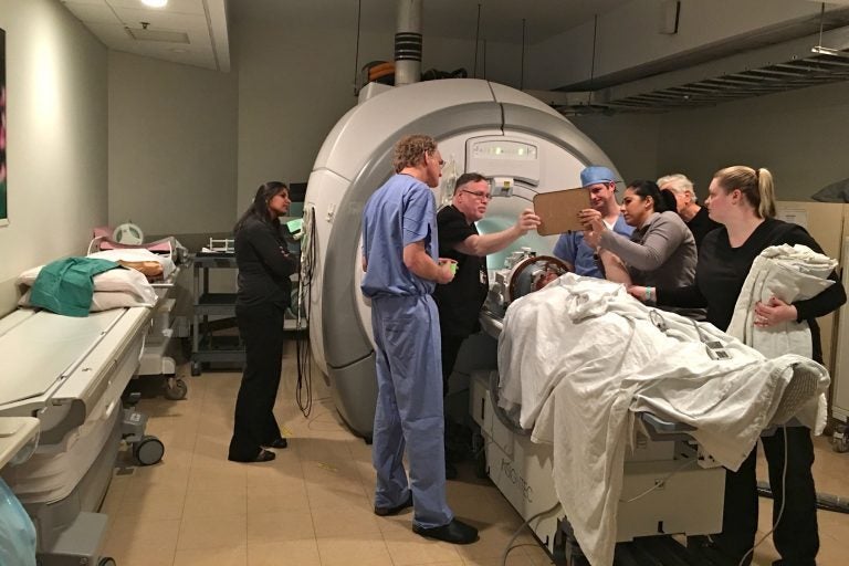 Dr. Gordon Baltuch and his team check on a patient throughout a procedure that uses a beam of ultrasound waves to stop his hand from trembling. (Kyrie Greenberg/WHYY)