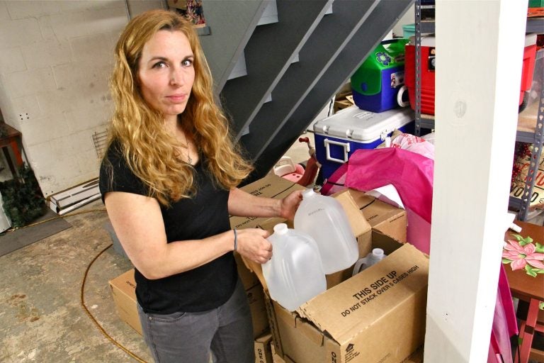 Jessica Cutaiar grabs a couple gallons of water from her basement of her Sellersville home. Her well water is undrinkable, contaminated with PFAs. (Emma Lee/WHYY)