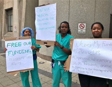 Anesthesiology residents Archana Gundigi, Rosemary De La Cruz, and Jo Linnen protest outside Hahnemann, demanding that management release their government funding to enable them to seek placements elsewhere. (Nina Feldman/WHYY)