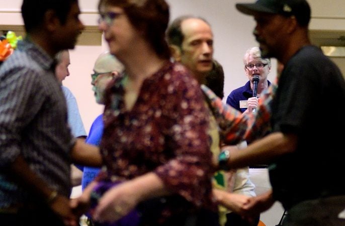 In the background Marilyn 'Zip' Warmerdam calls a 'tip' at a Center City hotel ballroom during the 36th annual LGBT Square Dance Convention. (Bastiaan Slabbers for WHYY)