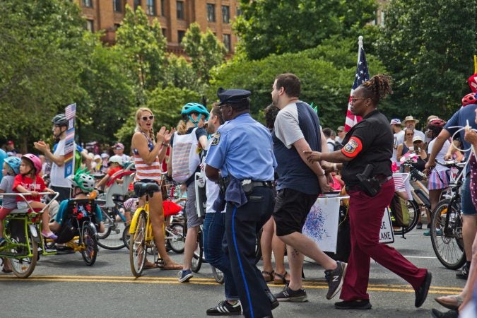 A protester demanding immigrants at the border be removed from detention centers is arrested at Philadelphia’s Fourth of July Parade. (Kimberly Paynter/WHYY)