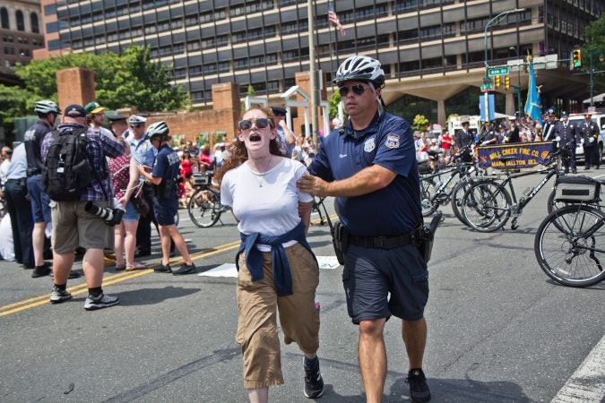 A protester demanding immigrants at the border be removed from detention centers is arrested at Philadelphia’s Fourth of July Parade. (Kimberly Paynter/WHYY)