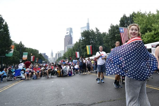 Sarah Weinhauser, an au-pair from Austria poses for a picture, draped in an American Flag at the Welcome America festival. (Bastiaan Slabbers for WHYY)