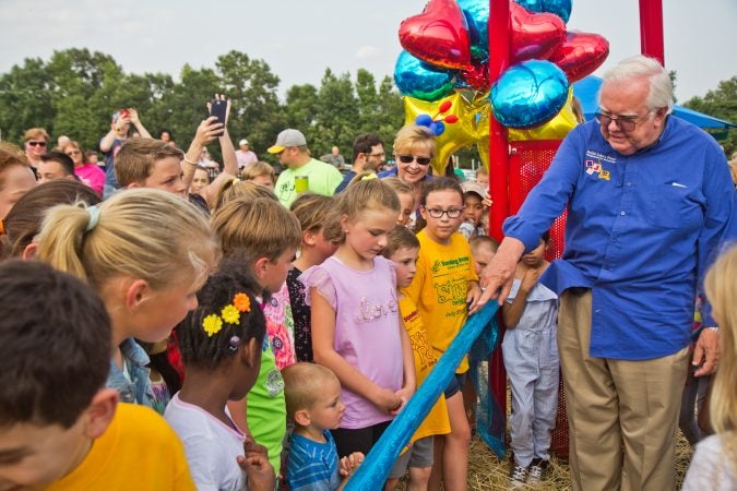 Jim and Lynn Cummings help a group of children cut the ribbon at Delran’s Jake’s Place. (Kimberly Paynter/WHYY)