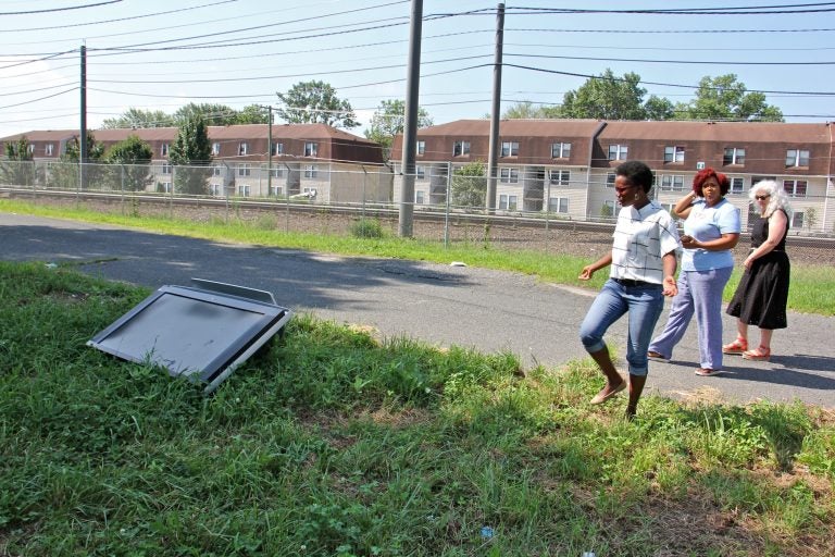 A discarded television lies in a vacant lot off Pershing Street near the PATCO rail tracks. Activists (from left) Vedra Chandler, Meishka Mitchell and Noreen Scott Garrity, are working to stop the practice of illegal dumping on Camden lots. (Emma Lee/WHYY)