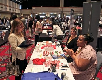 Stephanie Burton (right) of the Dialysis Center of Philadelphia, recruits nurses during the Hire Hahnemann career fair put on by Philadelphia Works at the Pennsylvania Convention Center. (Emma Lee/WHYY)