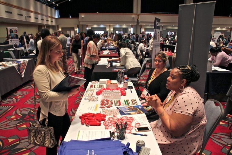 Stephanie Burton (right) of the Dialysis Center of Philadelphia, recruits nurses during the Hire Hahnemann career fair put on by Philadelphia Works at the Pennsylvania Convention Center. (Emma Lee/WHYY)