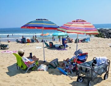 Beverly Jaker of Woodbridge (right) and her sister, Marilyn, lounge under beach umbrellas in Manasquan on July 29, 2019. (Nicholas Pugliese/WHYY)