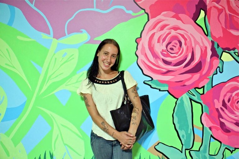 Becky Green, 27, stands in front of the mural she helped to create in SEPTA Suburban Station. (Emma Lee/WHYY)