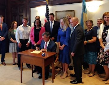 Gov. John Carney signing the legislation expanding access to who can adopt in Delaware (Zoë Read/WHYY)