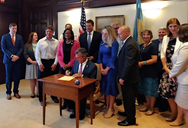 Gov. John Carney signing the legislation expanding access to who can adopt in Delaware (Zoë Read/WHYY)