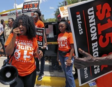 Noji Olaigbe, left, from the Fight for a $15 Minimum Wage movement speaks during a McDonald's workers strike as part of the nationwide movement, at the McDonald's at 27 West Broward Blvd. in Fort Lauderdale, Fla. on Thursday, May 23, 2019. (David Santiago/Miami Herald via AP)