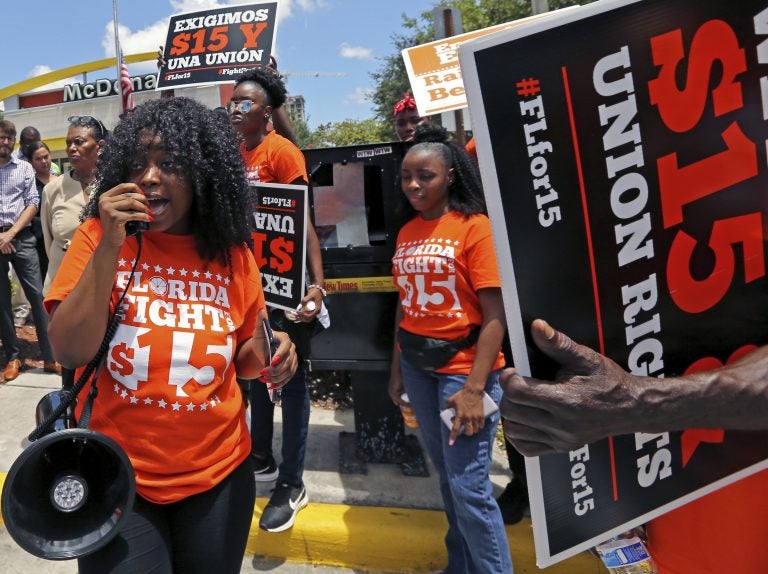 Noji Olaigbe, left, from the Fight for a $15 Minimum Wage movement speaks during a McDonald's workers strike as part of the nationwide movement, at the McDonald's at 27 West Broward Blvd. in Fort Lauderdale, Fla. on Thursday, May 23, 2019. (David Santiago/Miami Herald via AP)