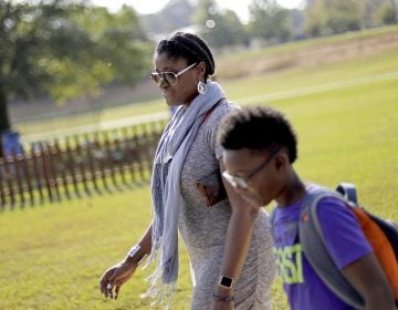 In this Oct. 11, 2017 file photo, Corrie Davis, left, picks up her son Turner from Big Shanty Elementary School in Kennesaw, Ga. The previous month, the school invited fifth-graders to dress up as characters from the Civil War. Davis says a white student dressed as a plantation owner approached her son and said 
