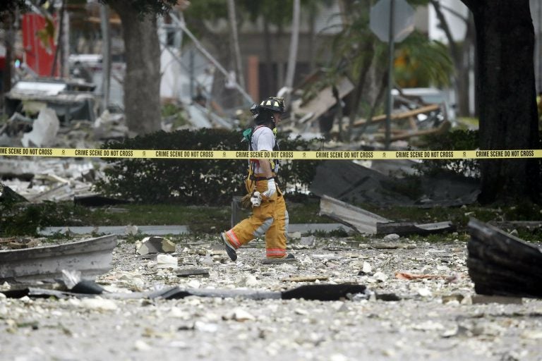 A firefighter walks through the remains of a building after an explosion on Saturday, July 6, 2019, in Plantation, Fla. Several people were injured after a vacant pizza restaurant exploded in the South Florida shopping plaza Saturday, according to police.  The restaurant was destroyed, and nearby businesses were damaged. (Brynn Anderson/AP Photo)