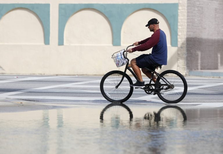 In this Oct. 9, 2018, file photo, a cyclist rides past an area flooded during a King Tide, an especially high tide, in Miami. Federal scientists, according to a report released Wednesday, July 10, 2019,  predict 40 places in the U.S. will experience higher than normal rates of so-called sunny day flooding this year due to rising sea levels and an abnormal El Nino weather system. (Wilfredo Lee/AP Photo, FIle)