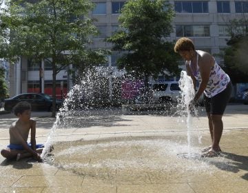 Karen Frazier of Capitol Heights, Md., right, and her son Amari Rogers, 11, left, play in a fountain in Washington, Saturday, July 20, 2019. The National Weather Service said 