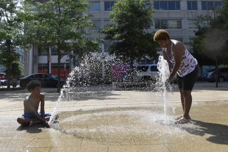 Karen Frazier of Capitol Heights, Md., right, and her son Amari Rogers, 11, left, play in a fountain in Washington, Saturday, July 20, 2019. The National Weather Service said 