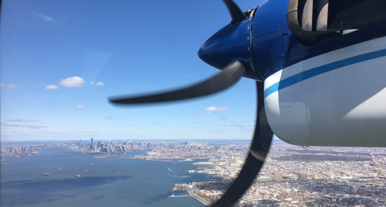 In this 2018 photo, a Twin Otter aircraft flies over New York Harbor and New York City on a research mission. In older Eastern US cities, nine times as much natural gas is leaking out of pipelines, homes than federal government had thought. (Eric Kort/University of Michigan via AP)